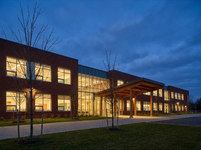 A school building at dusk with lit classroom windows