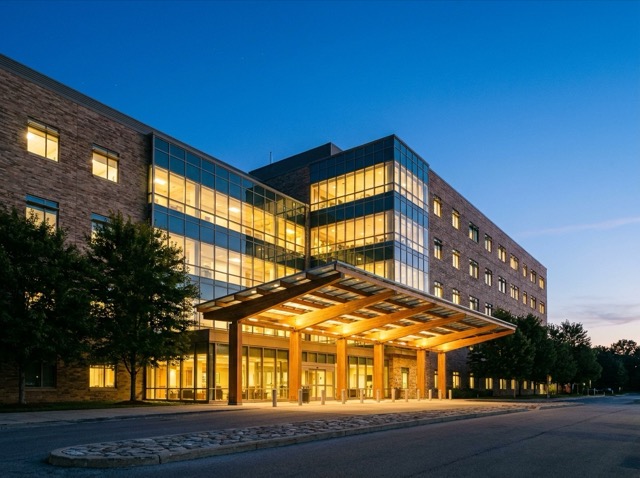 A hospital entrance at dusk with a lit canopy